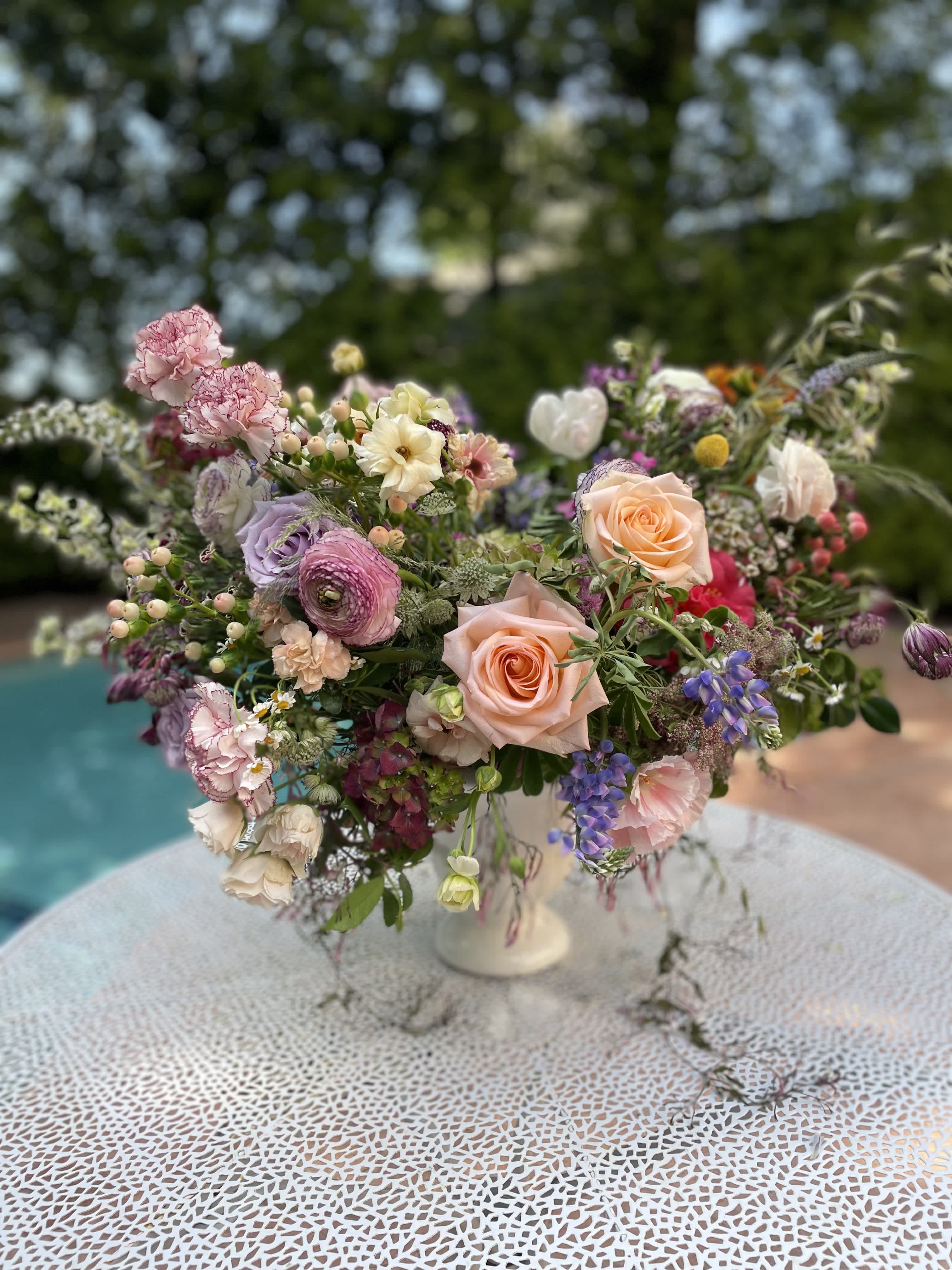 Mixed pastel flower arrangement in a white pedestal vase
