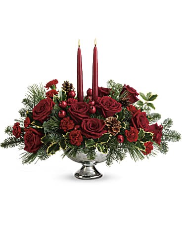 Red rose centerpiece with two lit taper candles in a silver bowl