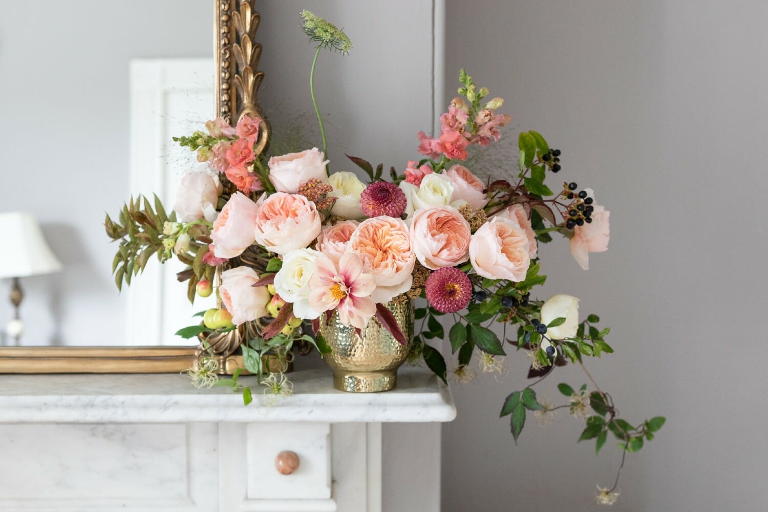 Blush and peach floral arrangement in a gold vase