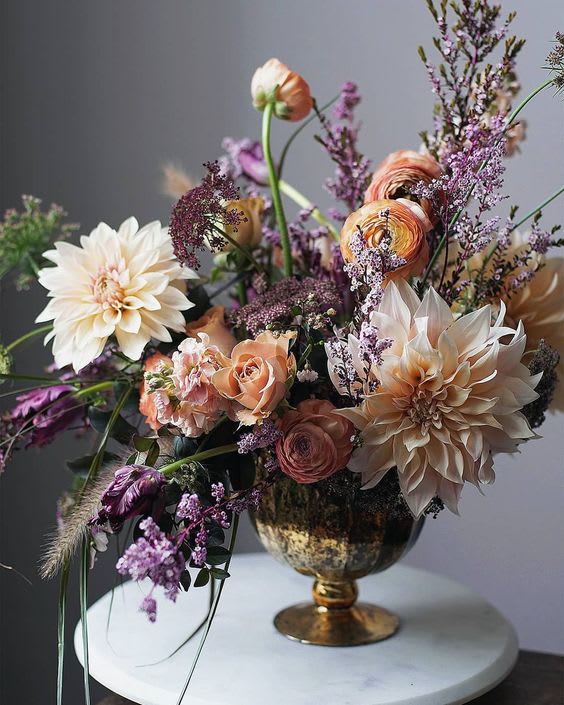 Peach and cream floral arrangement in a gold vase