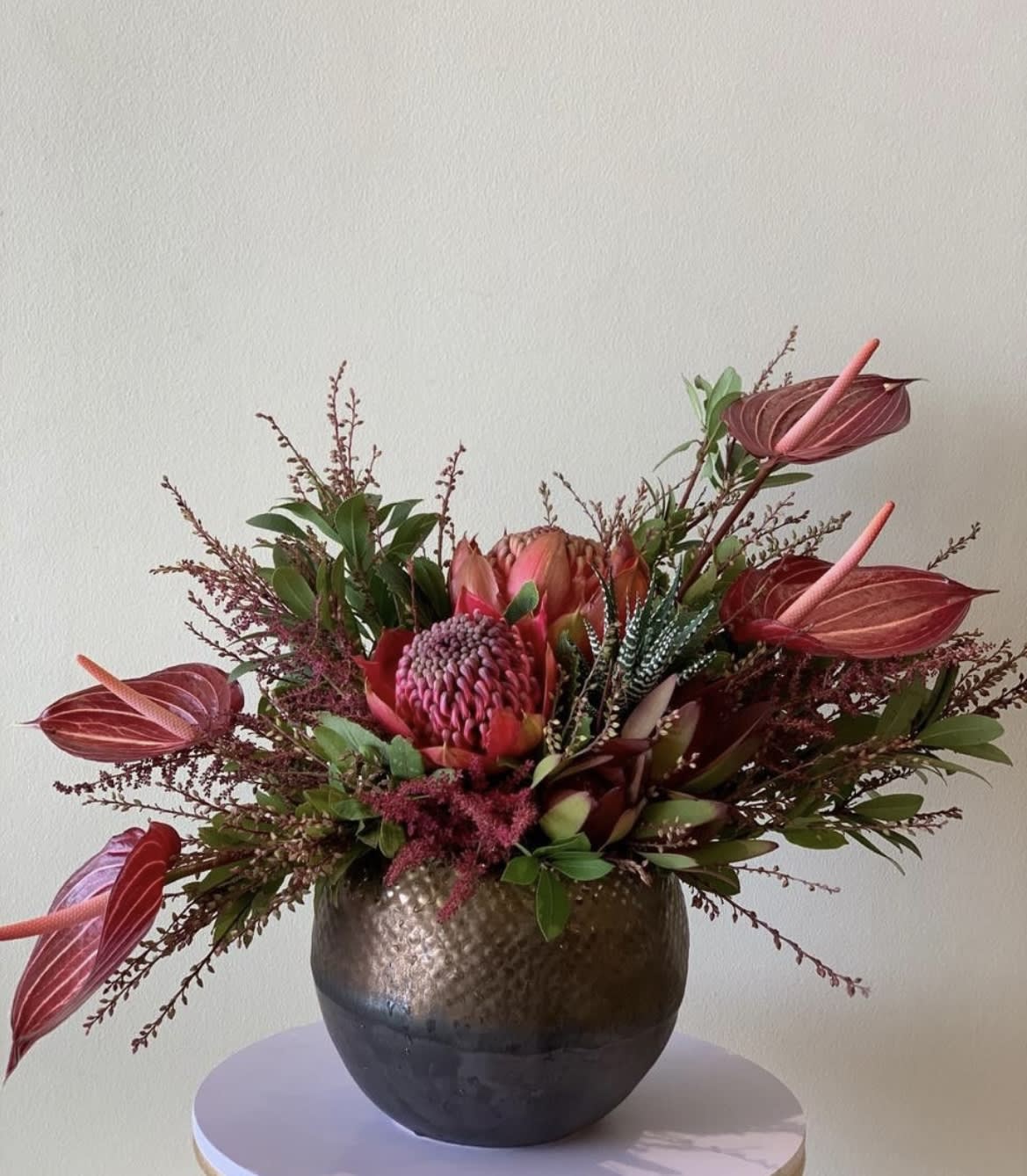 Tropical floral arrangement in a round metallic vase with pink blooms