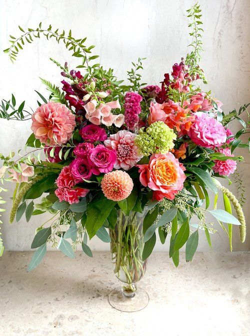 Large mixed bouquet of pink, peach, and orange flowers in a glass vase