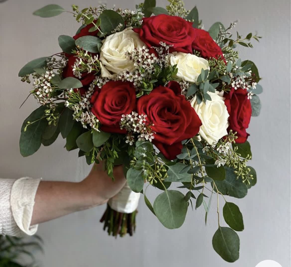 Bouquet of red and white roses with greenery and small white filler flowers