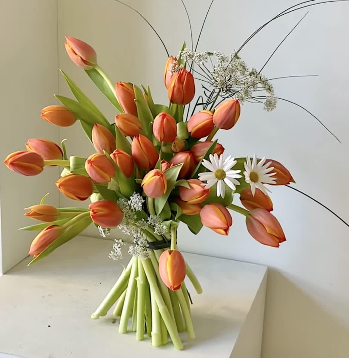 Bouquet of orange tulips with white daisies and airy filler
