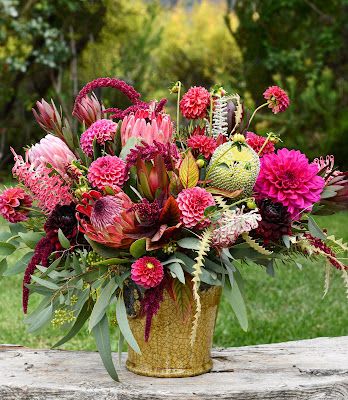 Bright pink and burgundy floral arrangement in a gold vase