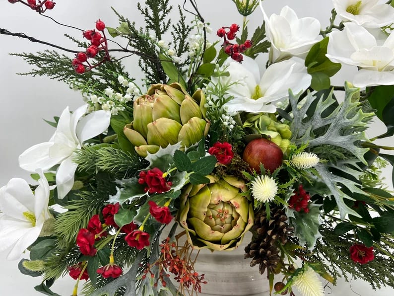 White flowers and artichokes in a festive holiday arrangement