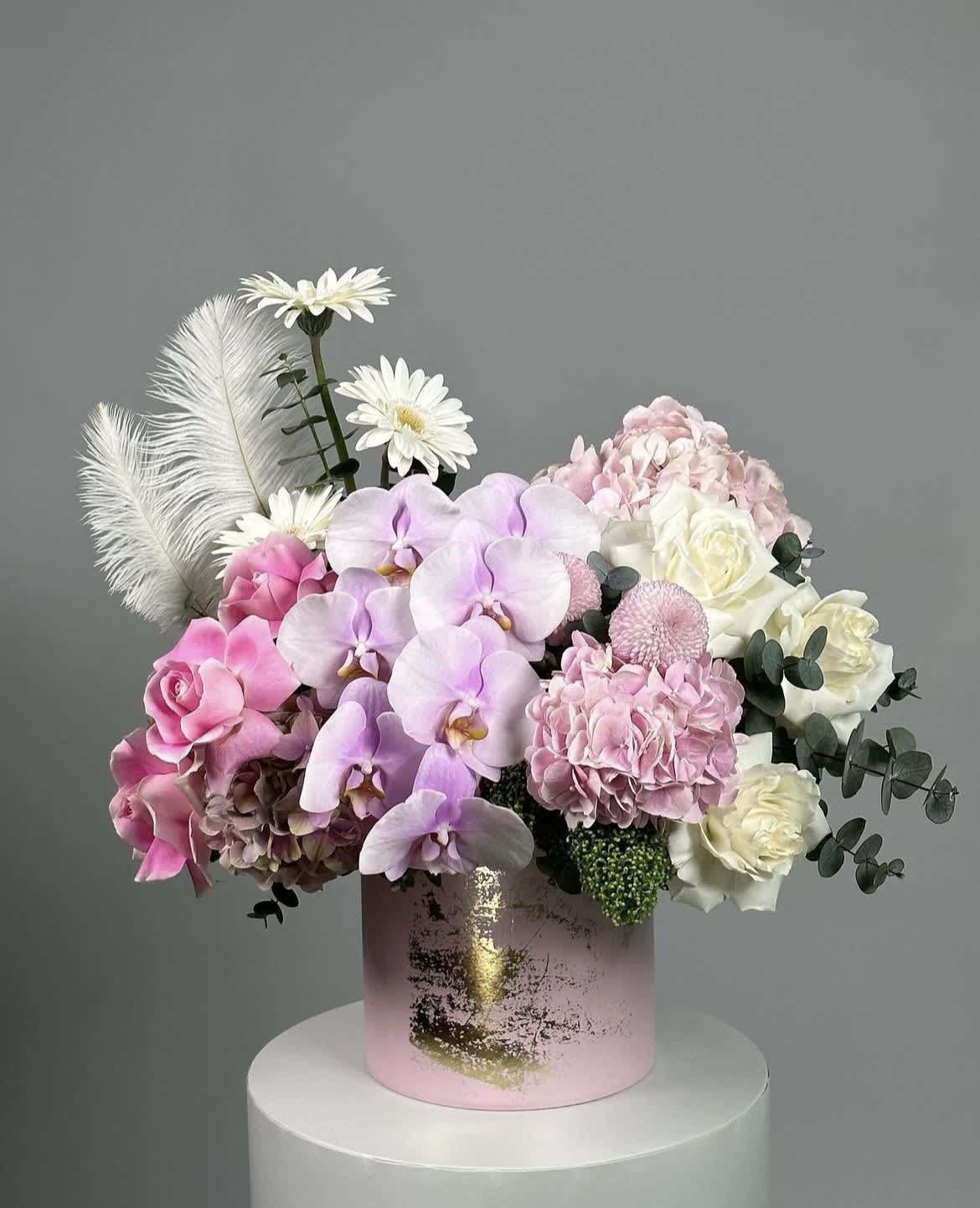 Pink and white floral arrangement in a pink cylindrical box