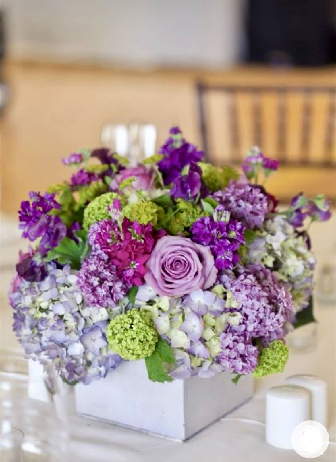 Lavender and purple floral arrangement in a white box on a table