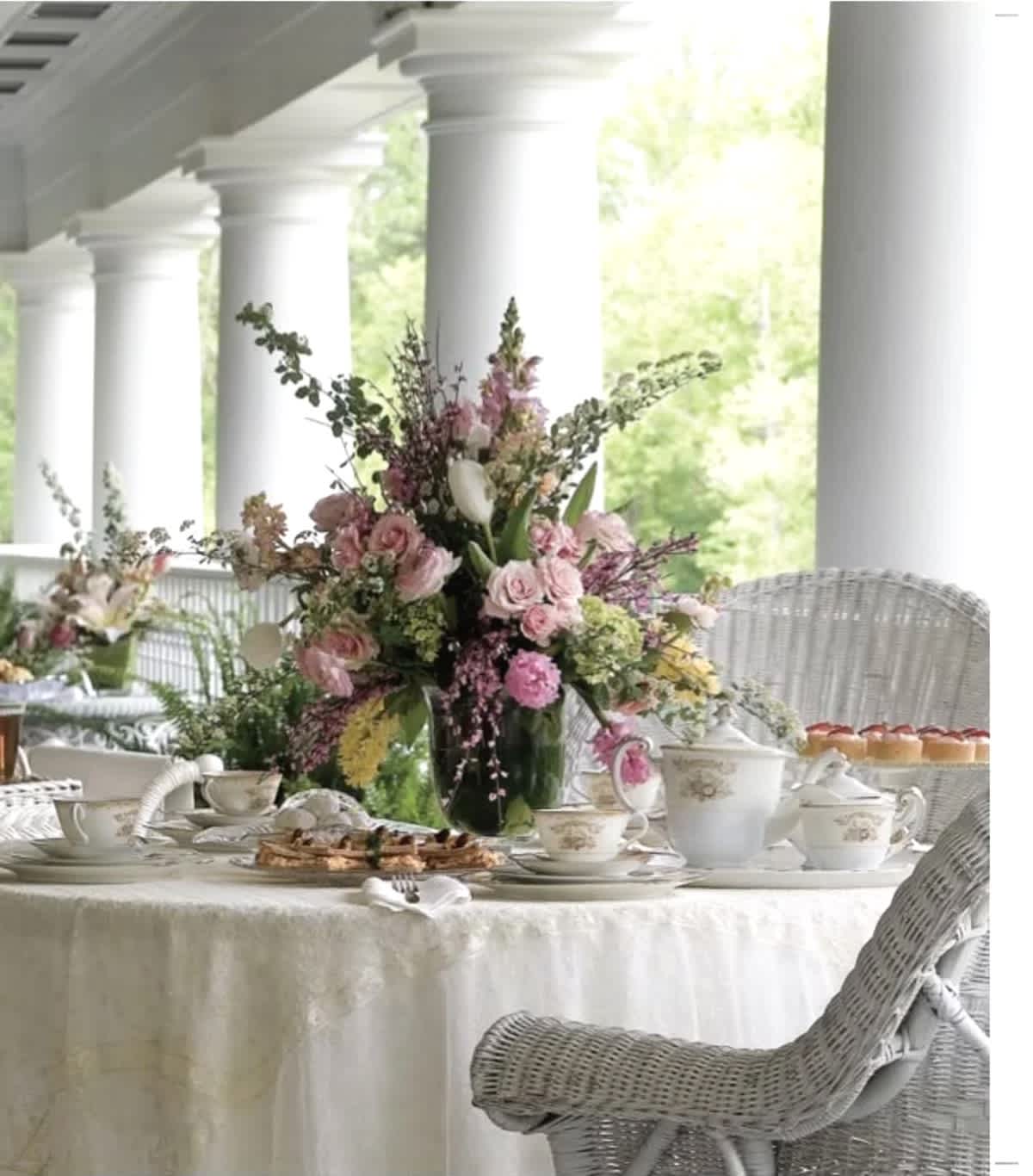 Tall pink and white floral centerpiece on a dining table with teacups