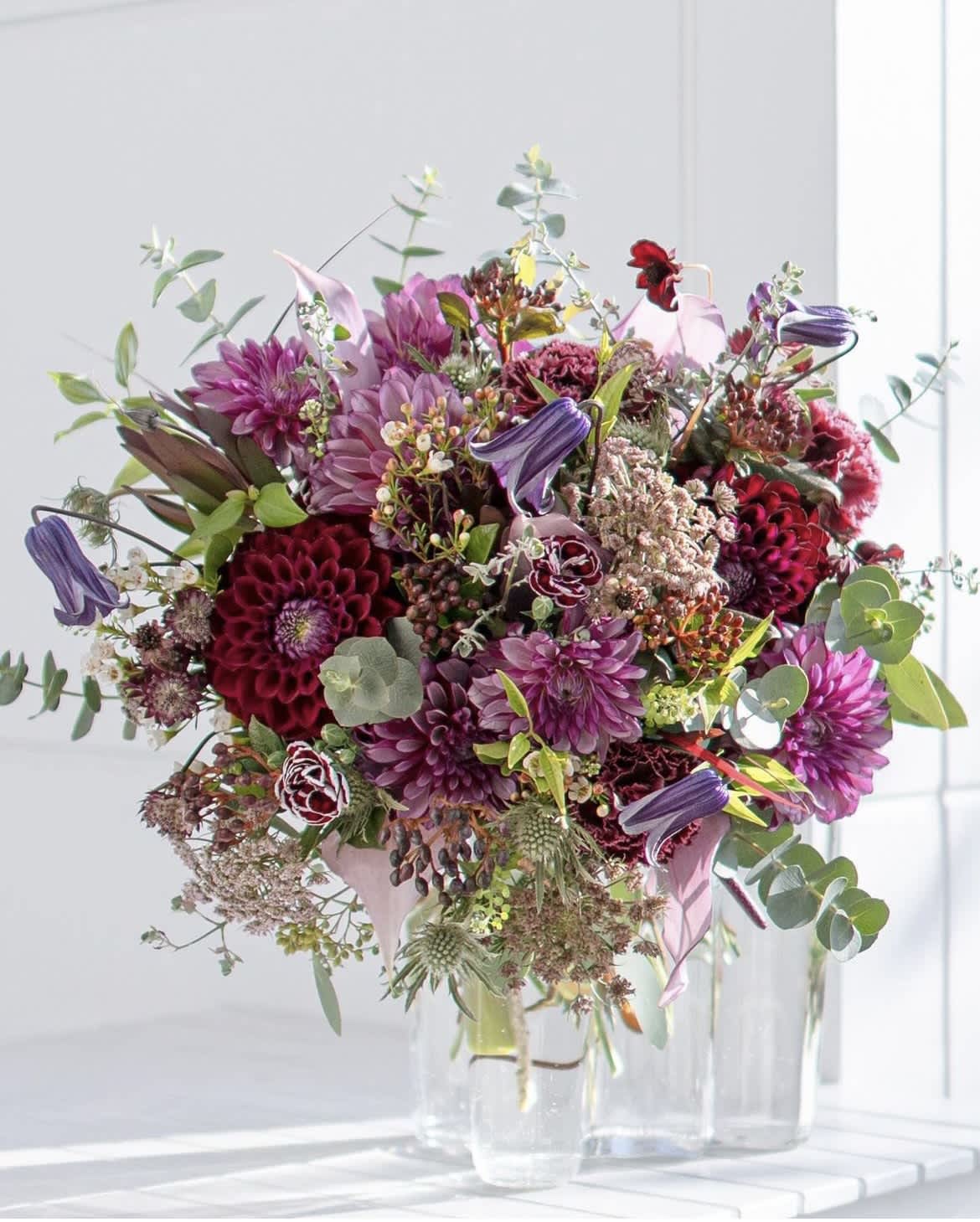 Bouquet of purple and burgundy flowers in a clear glass vase