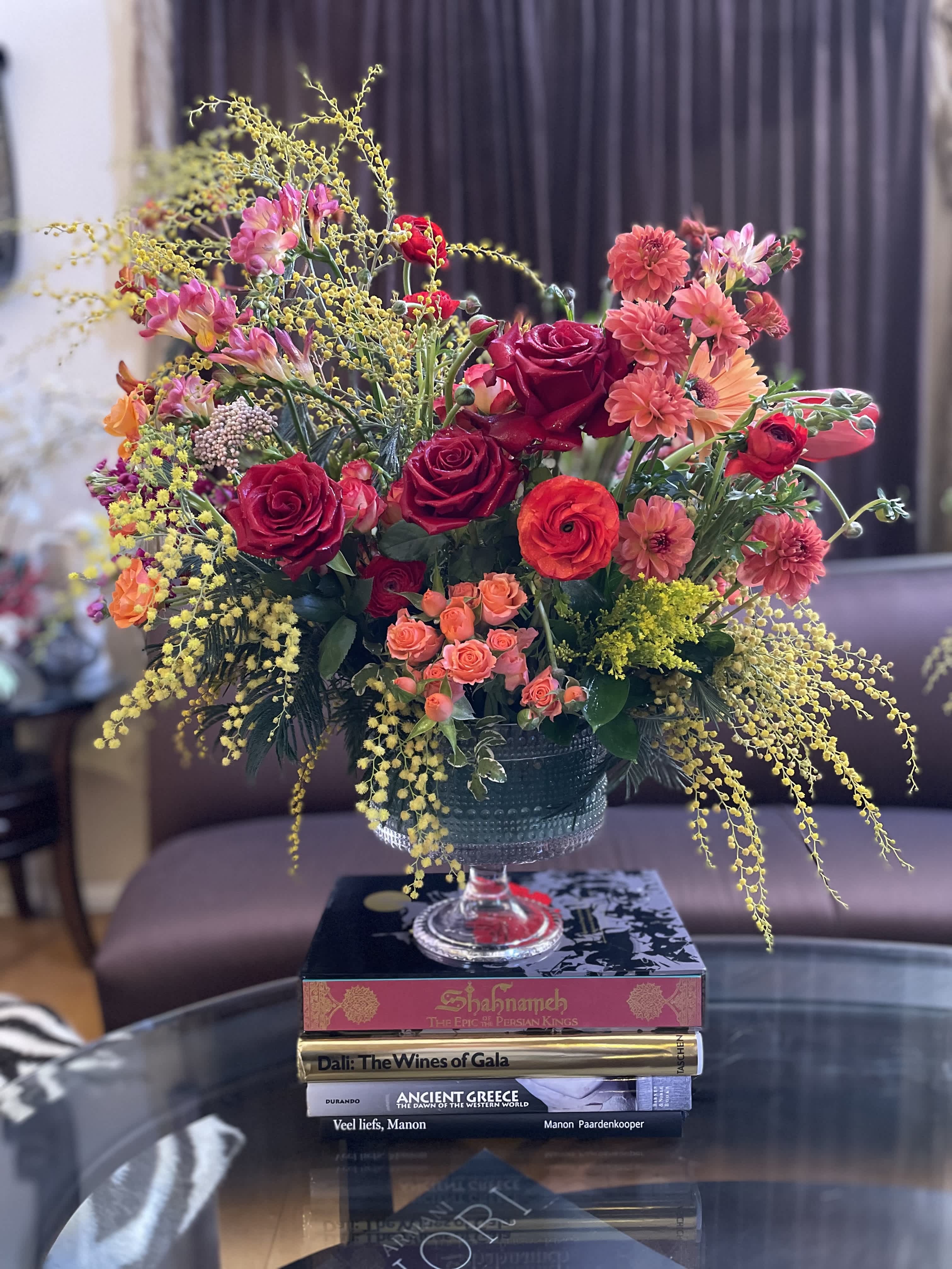 Mixed bouquet of red and pink flowers in a glass compote vase