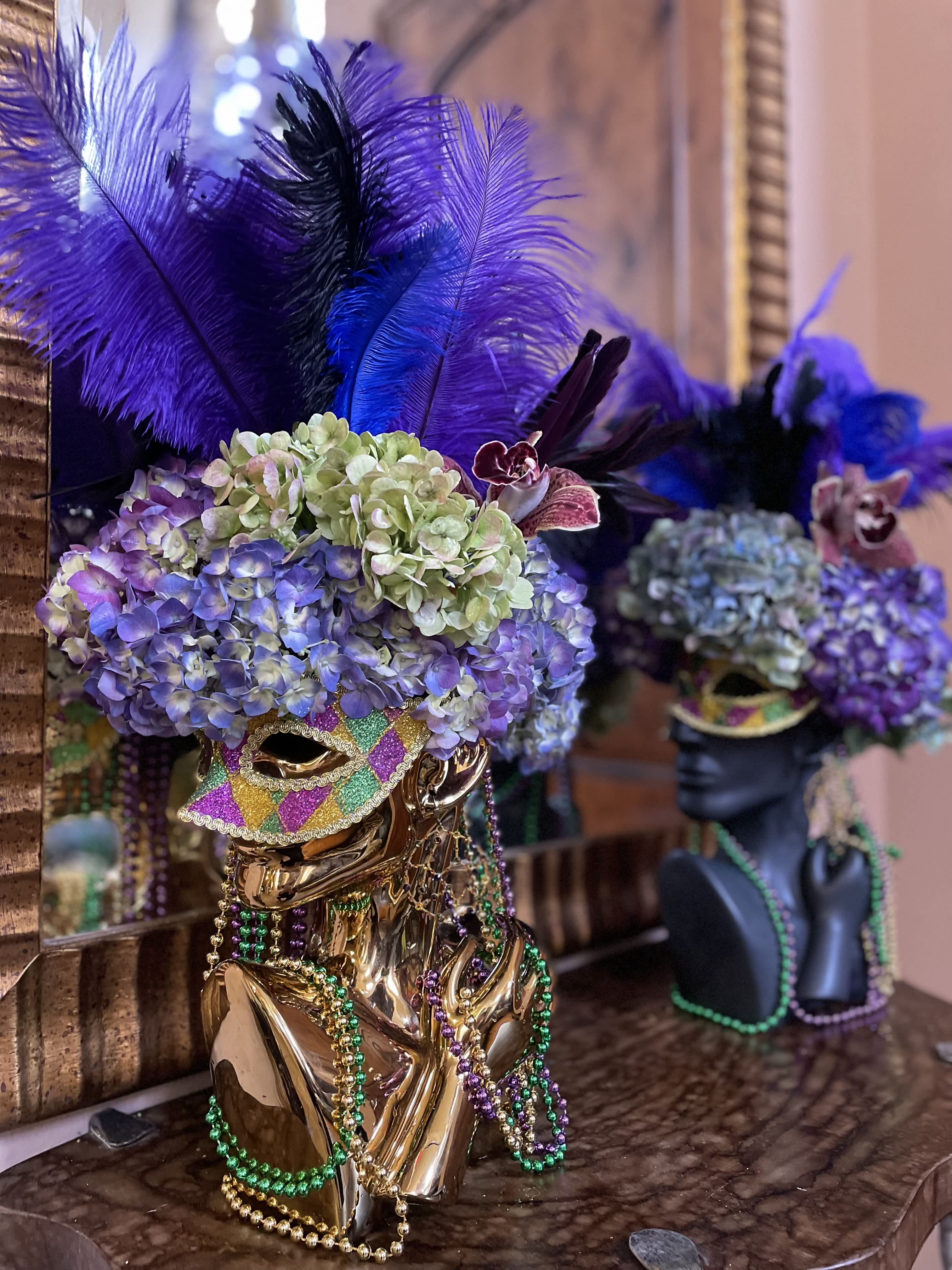 Decorative mask topped with purple hydrangeas and feathers