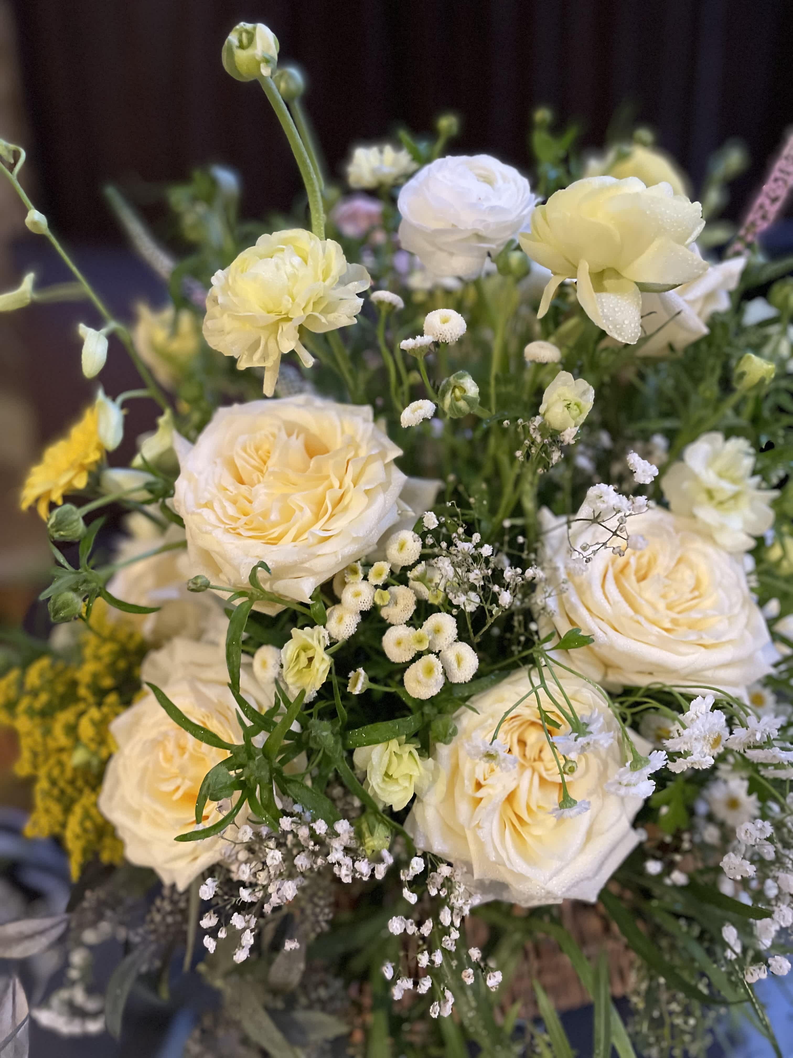 Cream roses and small white filler flowers in a loose bouquet