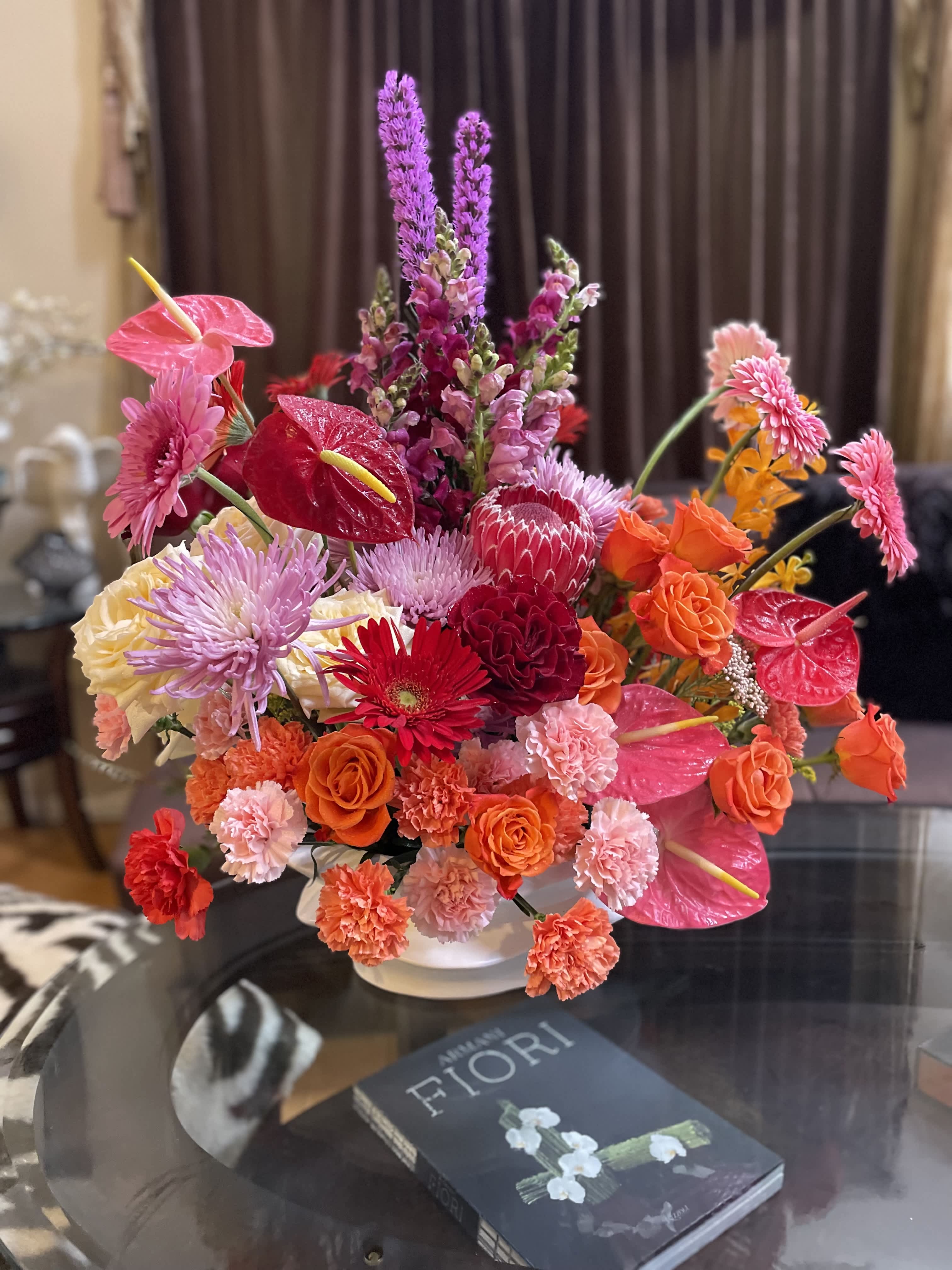 Bright mixed bouquet in a white vase with pink and orange blooms