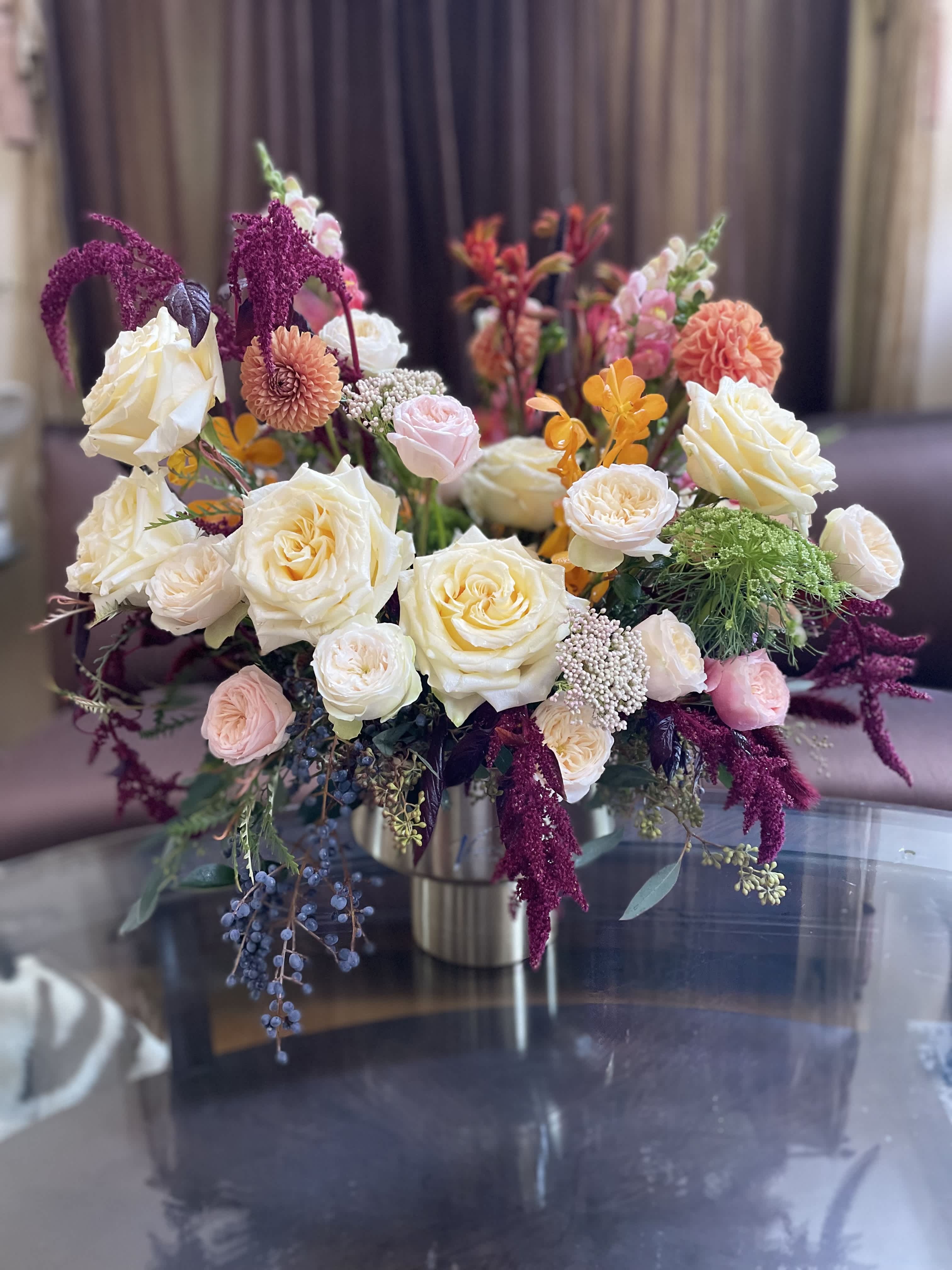 Mixed bouquet of cream, pink, and orange flowers in a metal vase