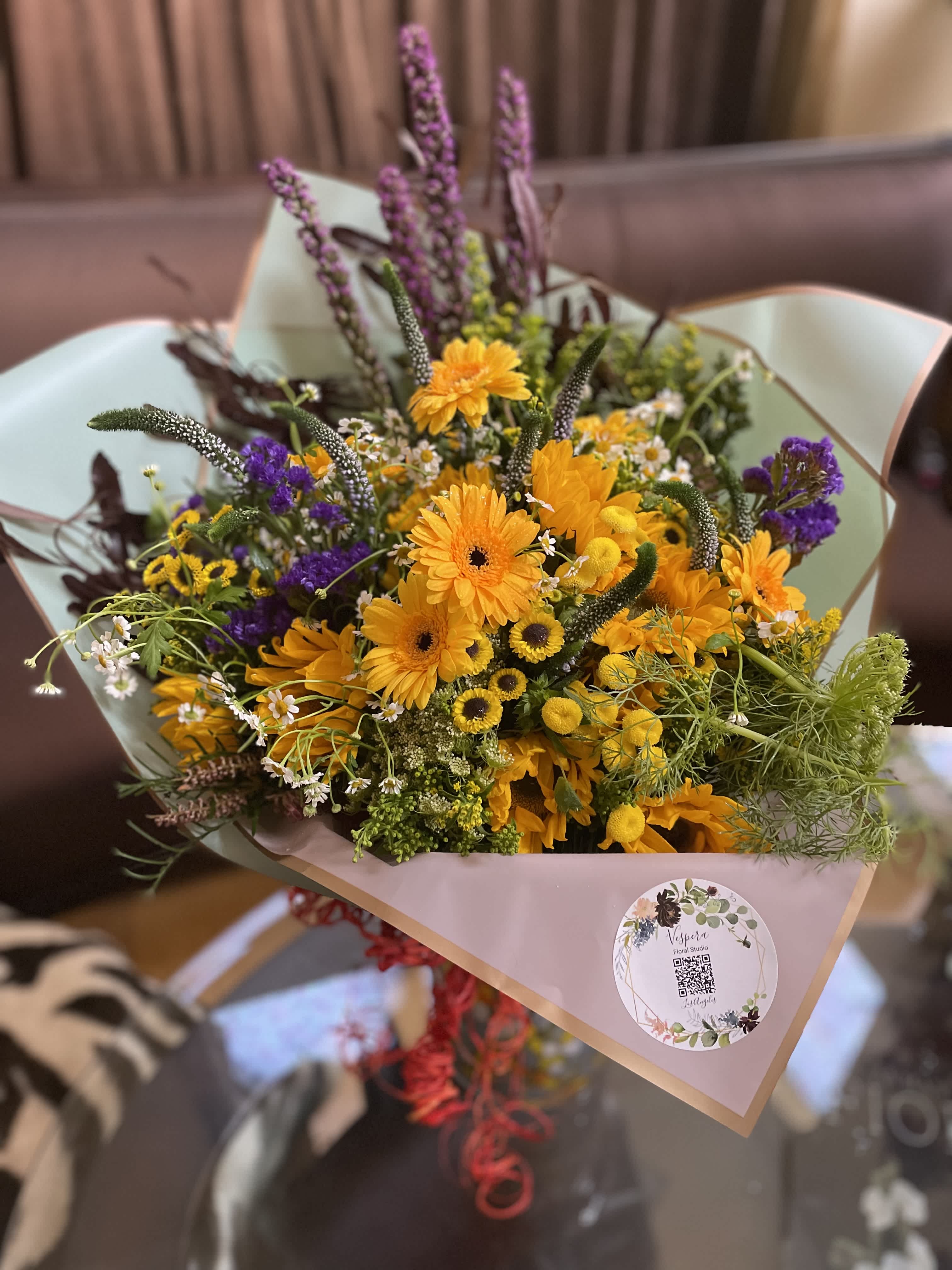 Bouquet of yellow and purple flowers wrapped in pale paper