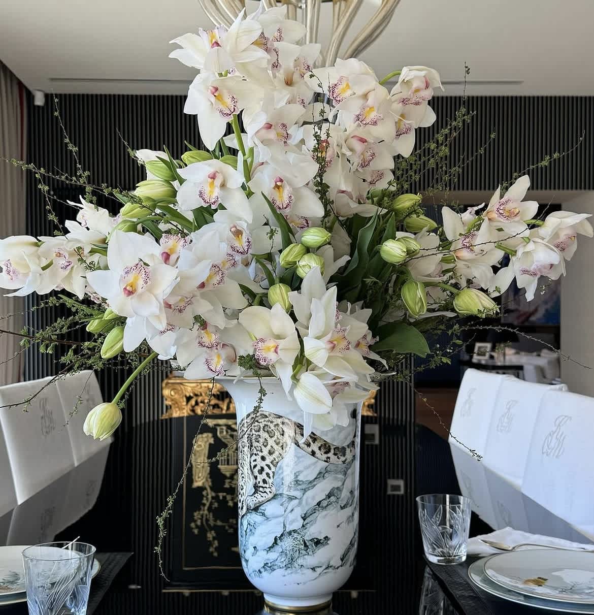 Large white orchid arrangement in a decorative vase on a dining table