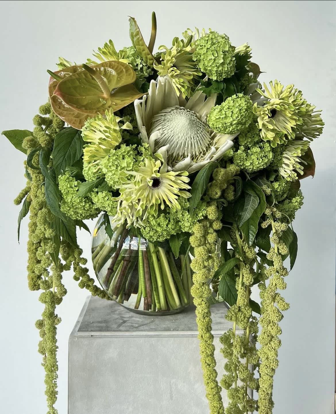 Green floral arrangement in a glass vase with cascading blooms
