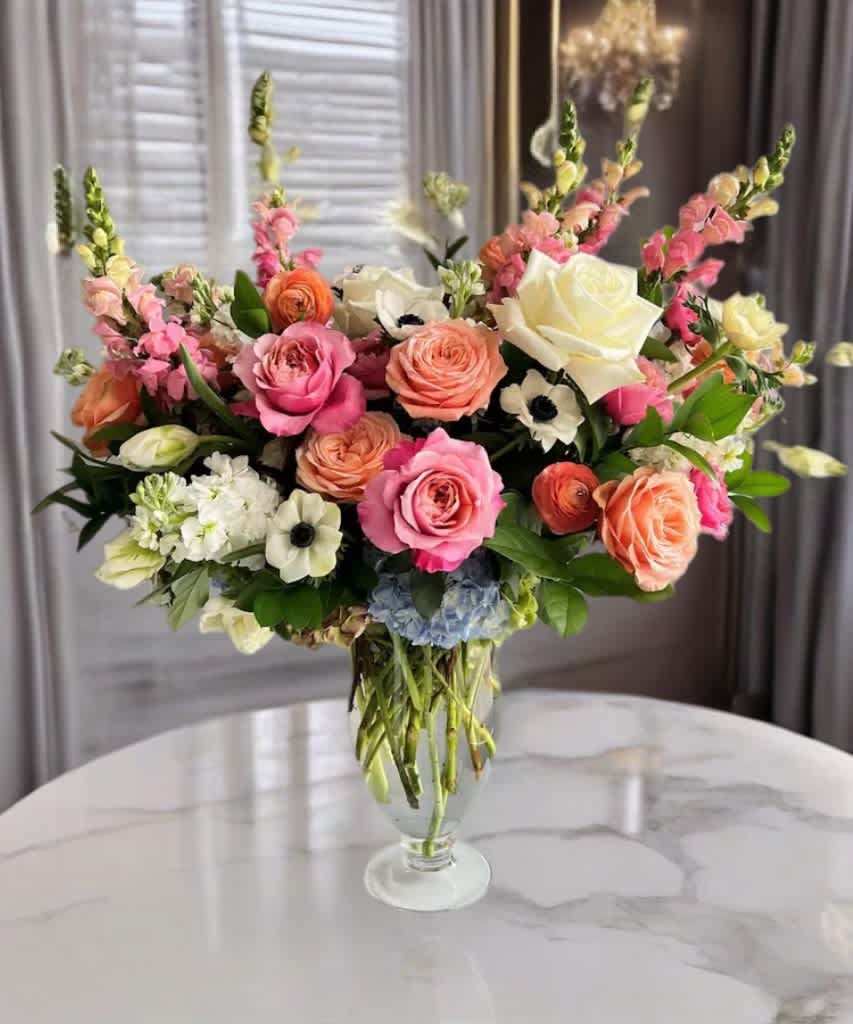 Mixed pink and peach flowers arranged in a clear glass vase