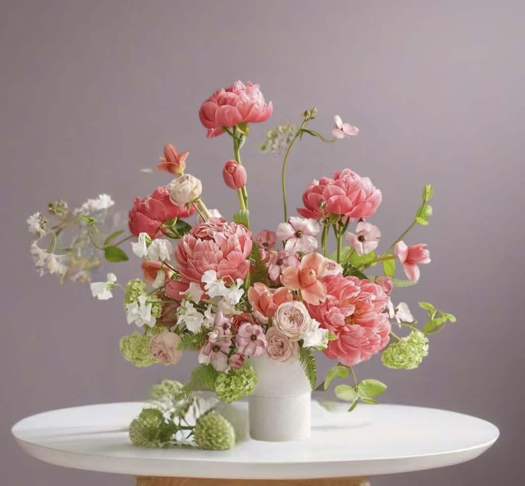 Pink and peach floral arrangement in a white vase