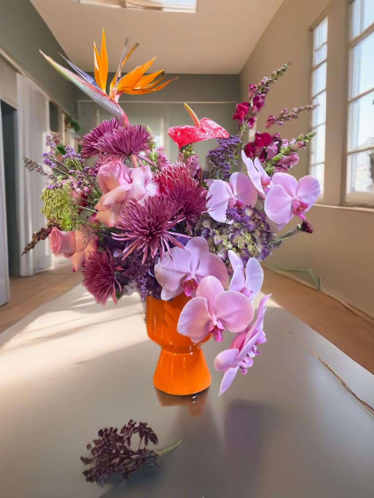 Colorful bouquet in an orange vase with orchids and tropical blooms