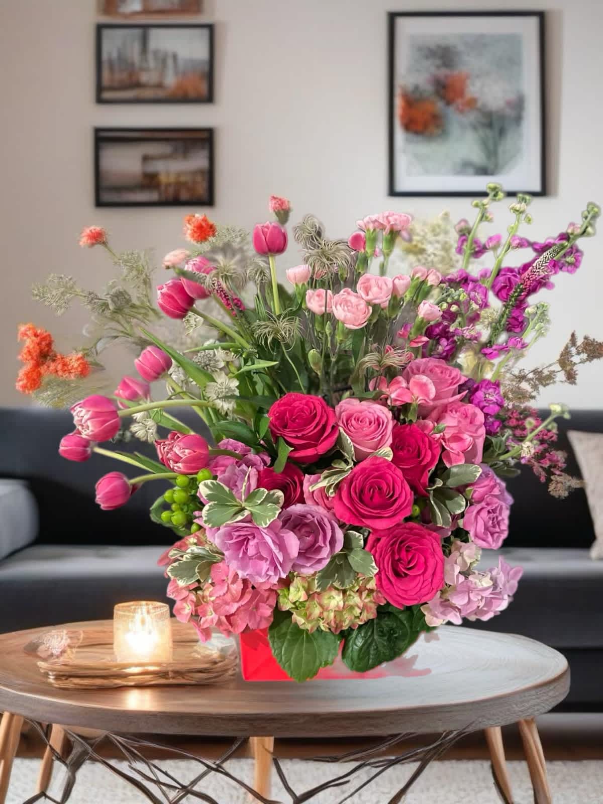 Pink and purple mixed flower arrangement in a red box on a table