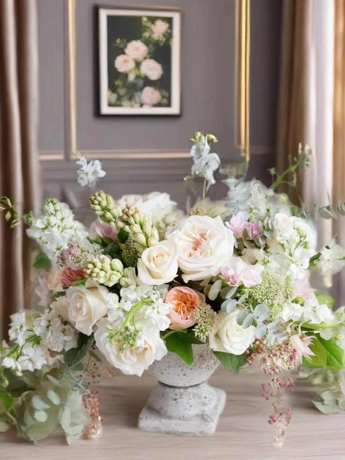 Pastel floral arrangement in a stone pedestal vase
