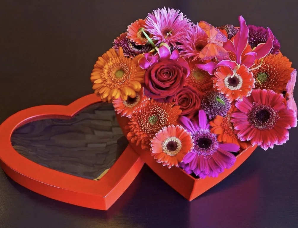 Heart-shaped box with bright mixed flowers and a red rose