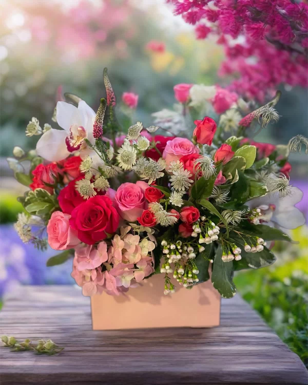 Pink and red roses arranged in a peach box with white accent flowers