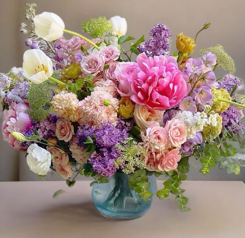 Mixed pink, purple, and white flowers in a blue glass vase