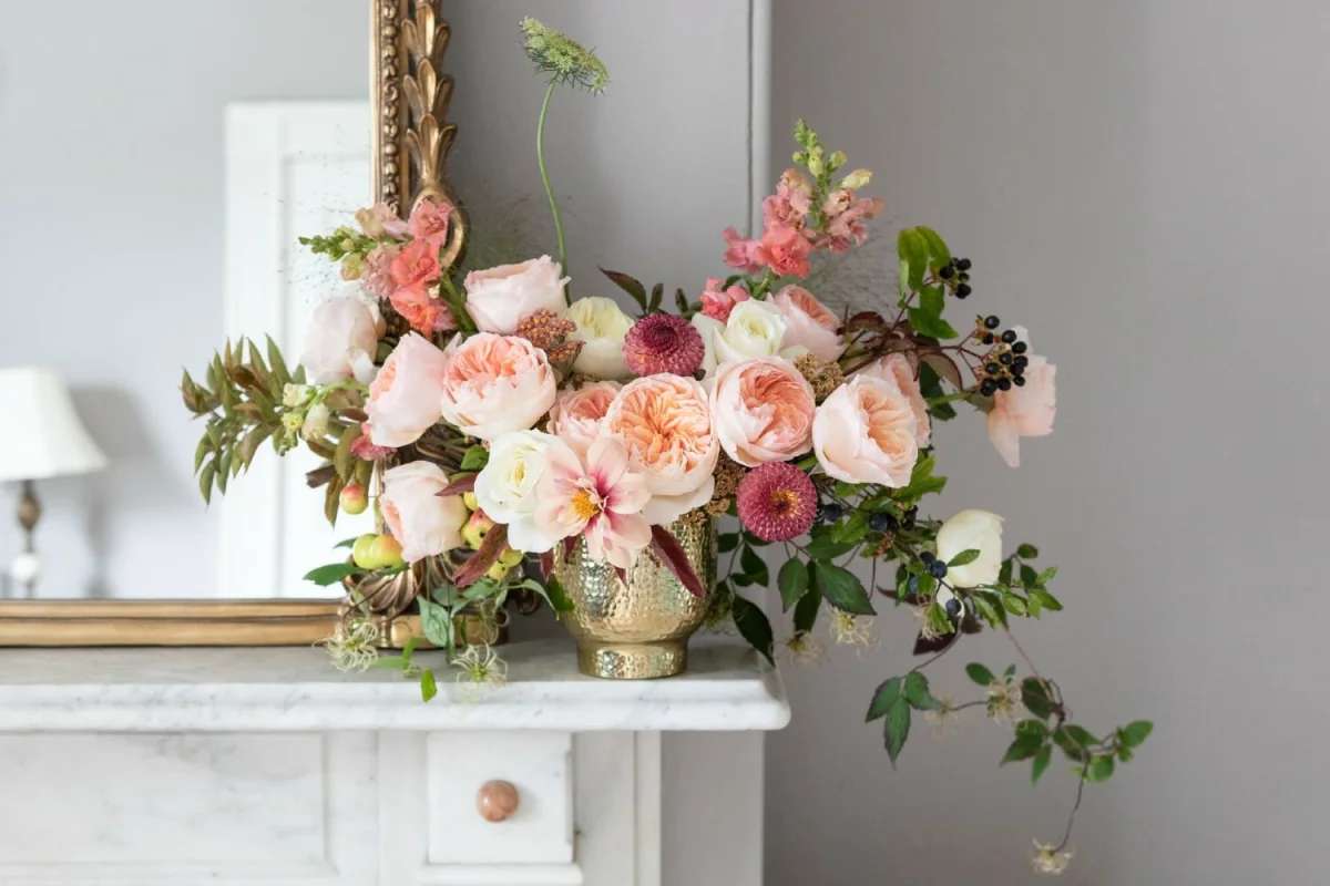 Blush and peach floral arrangement in a gold vase