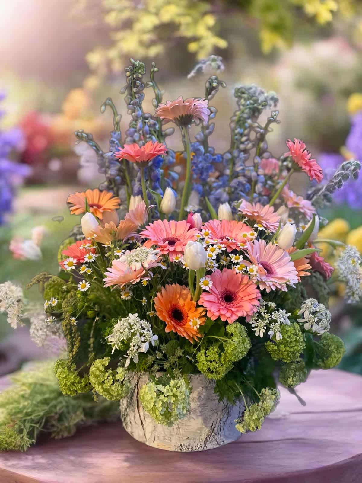 Mixed pink and orange flowers in a rustic vase