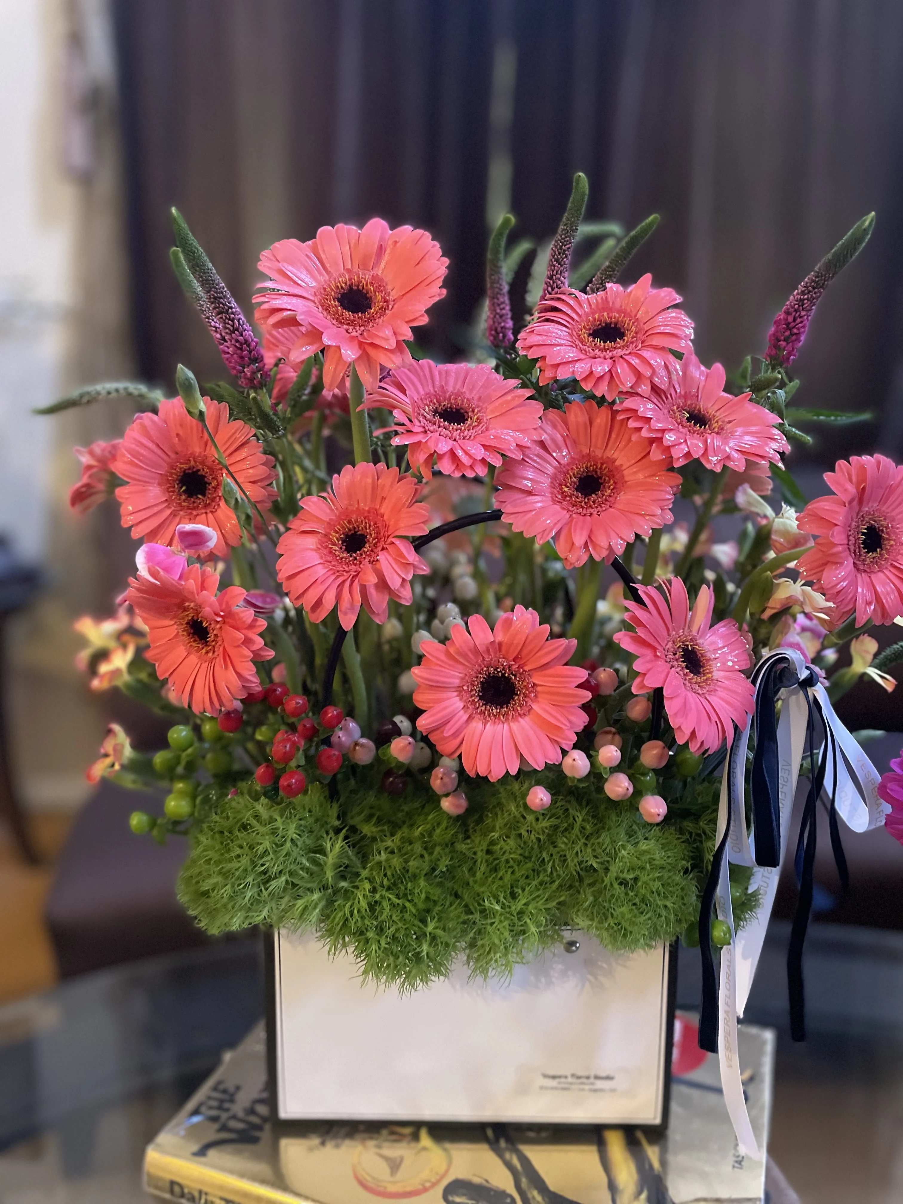 Pink gerbera daisies arranged in a white box with green moss
