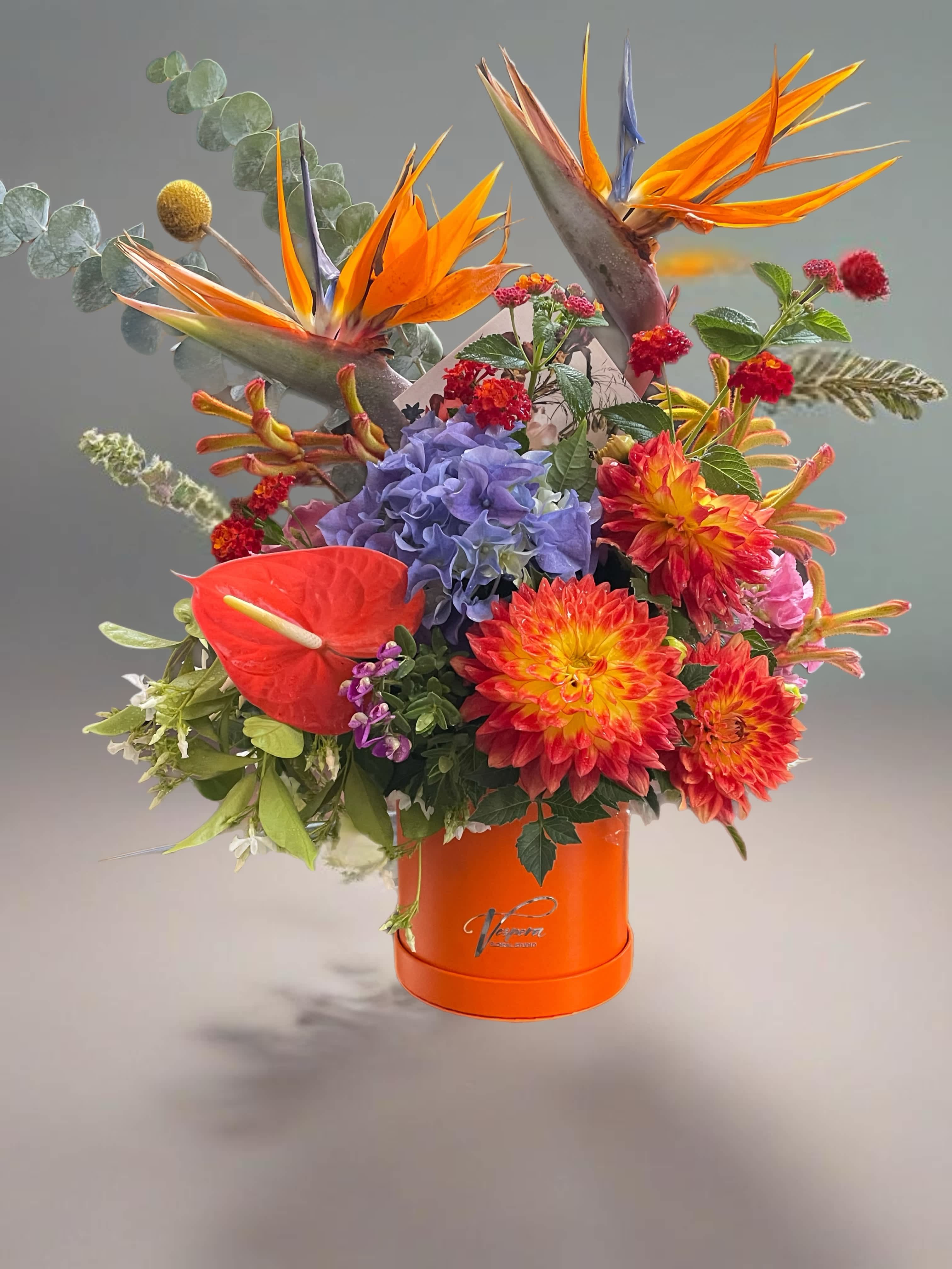 Tropical bouquet with orange bird-of-paradise and dahlias in an orange box