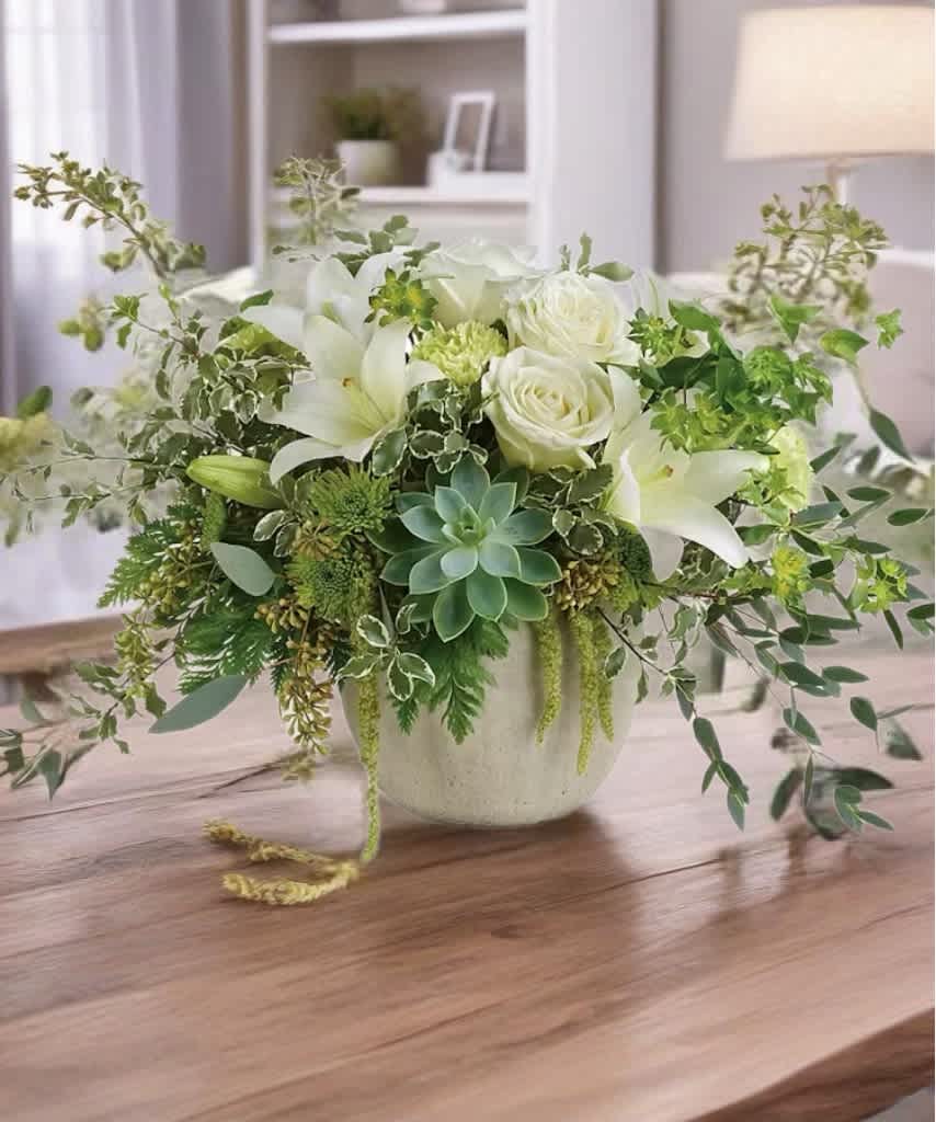White roses and lilies in a ceramic vase with trailing greenery