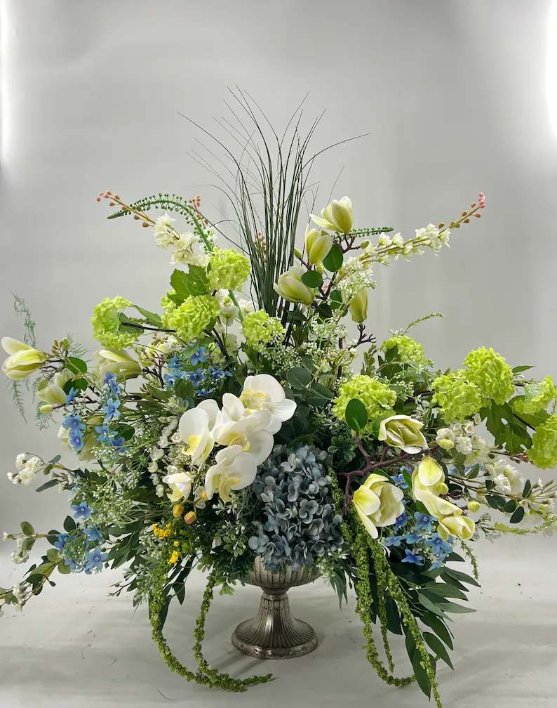 Large floral arrangement in a silver urn with white orchids and green blooms