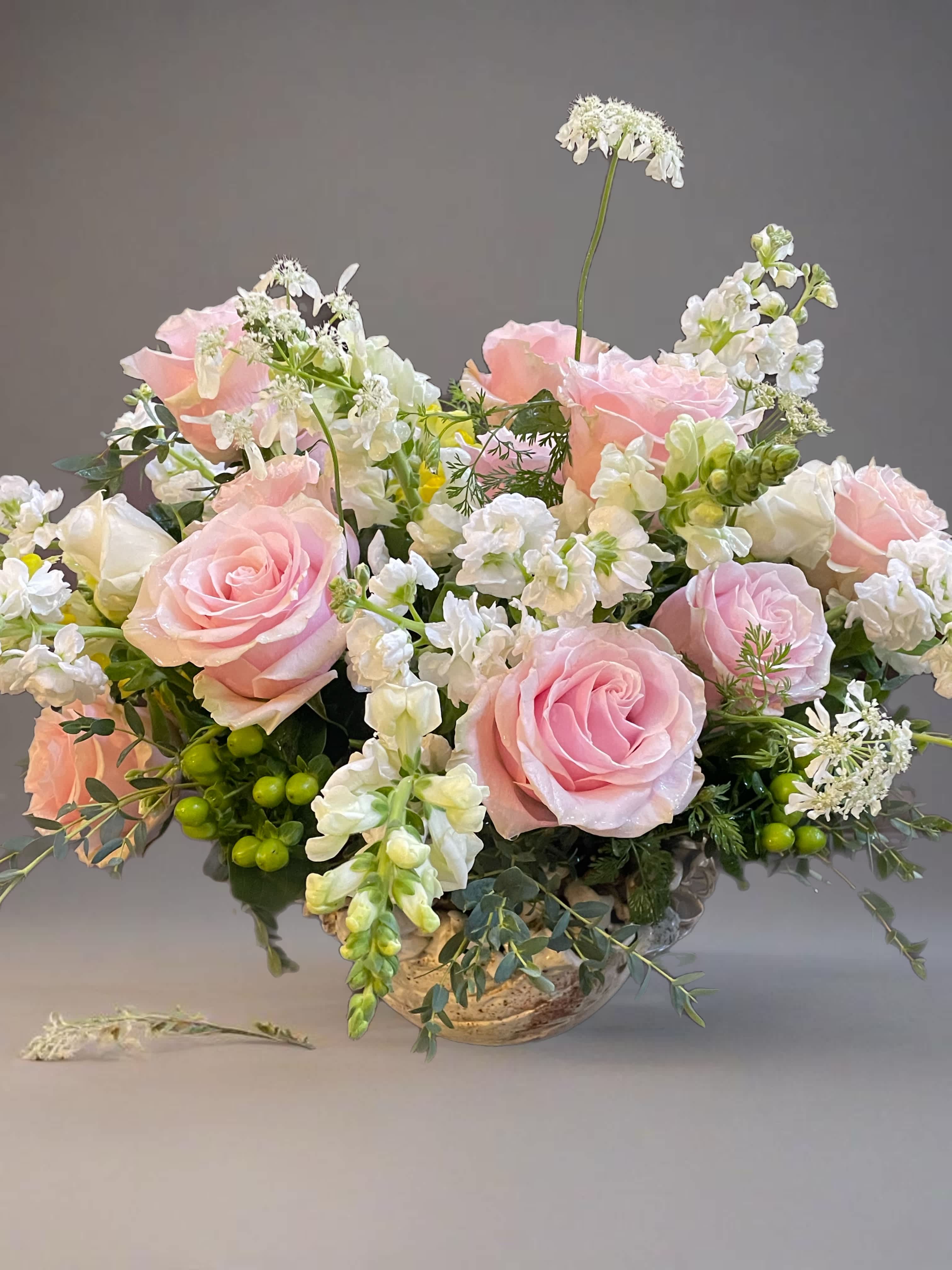Pink roses and white flowers arranged in a low vase
