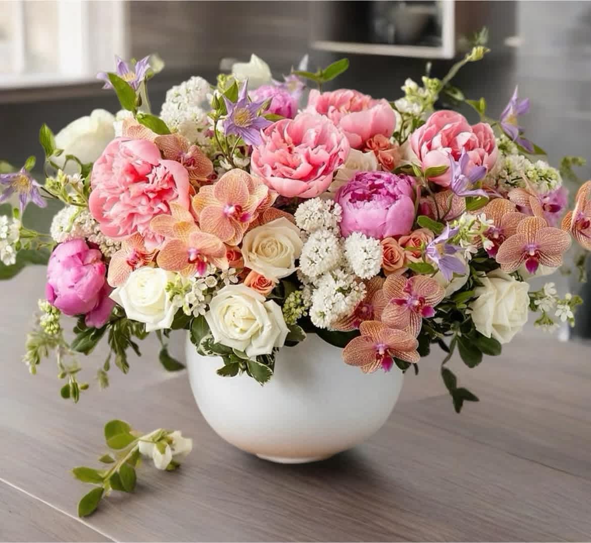 Pink and white floral arrangement in a white bowl vase