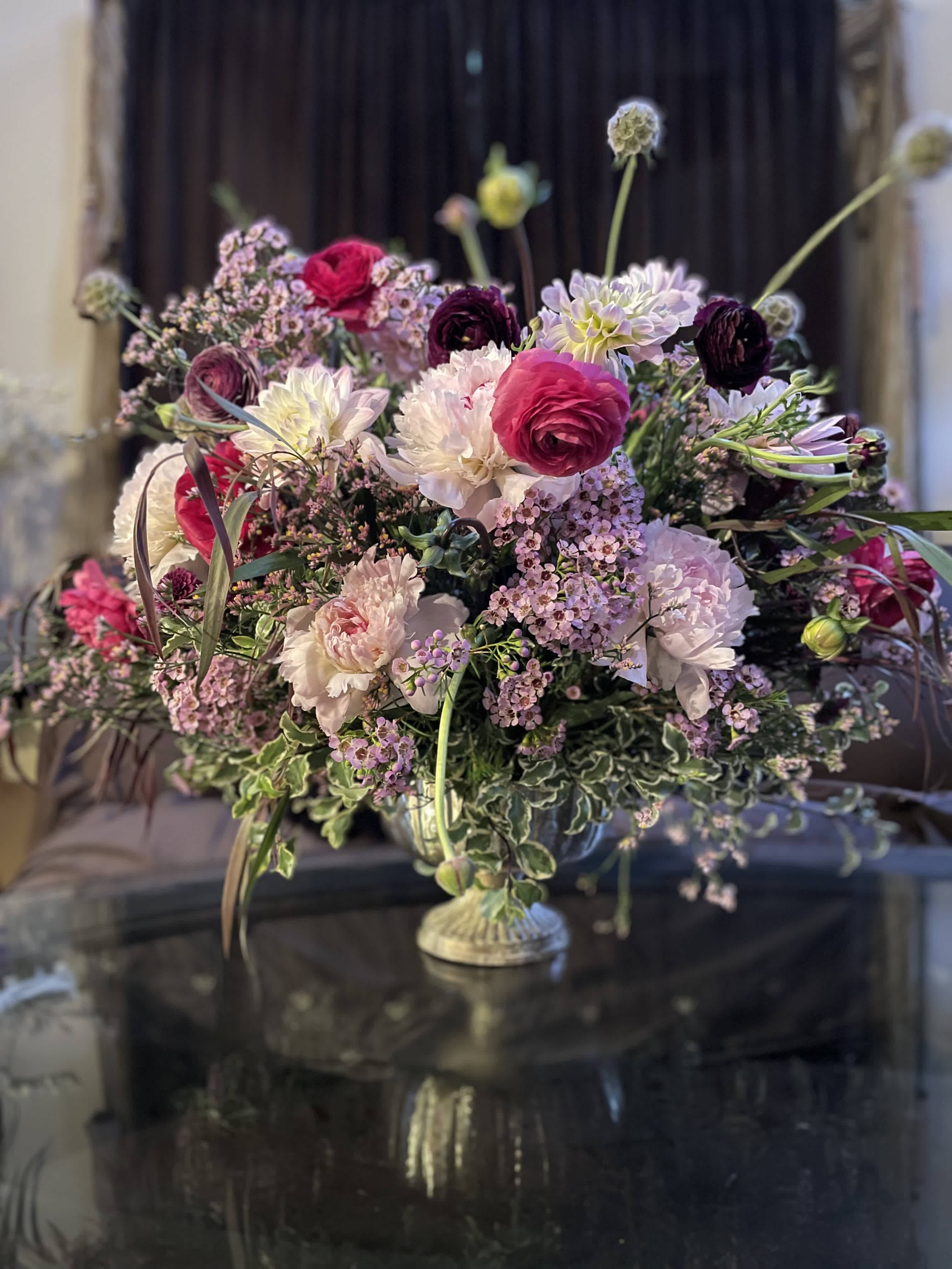 Large mixed floral arrangement in a pedestal vase with pink, white, and purple blooms