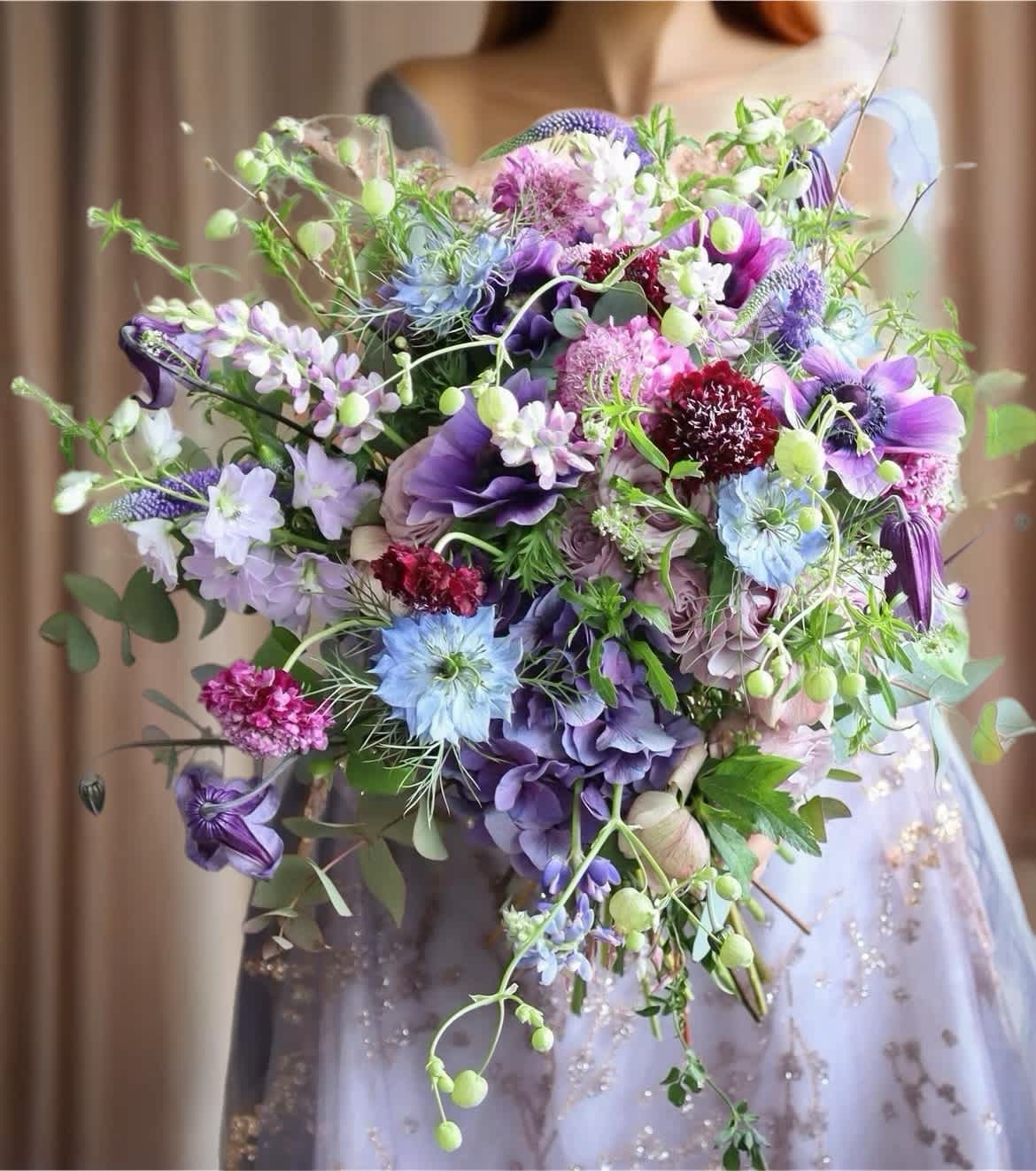Large bouquet of purple, blue, and pink flowers held by a person