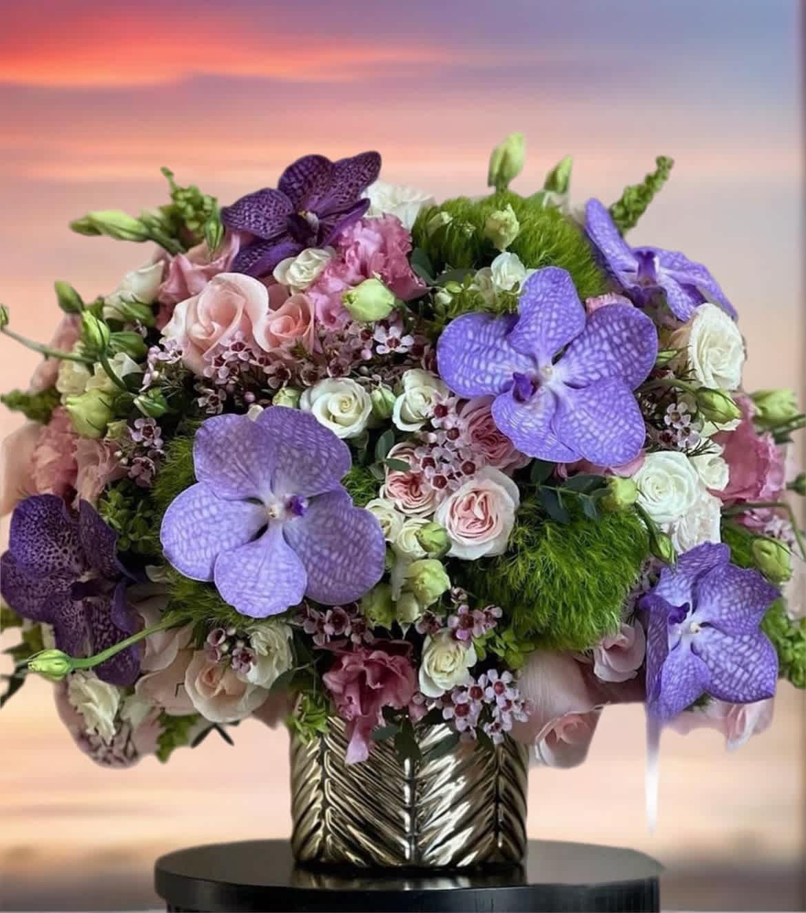 Bouquet of purple orchids and pink roses in a metallic vase
