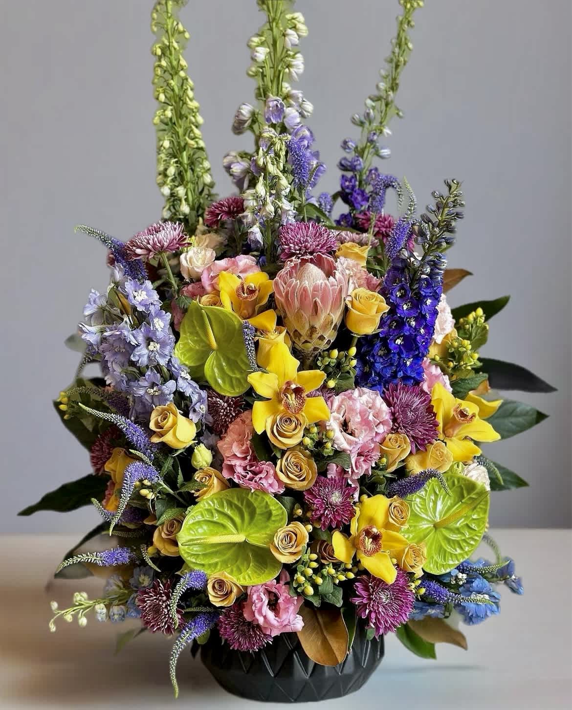 Colorful mixed bouquet in a black vase with tall purple and green spikes
