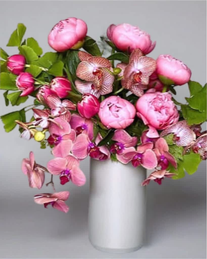 Pink peonies and orchids arranged in a white vase