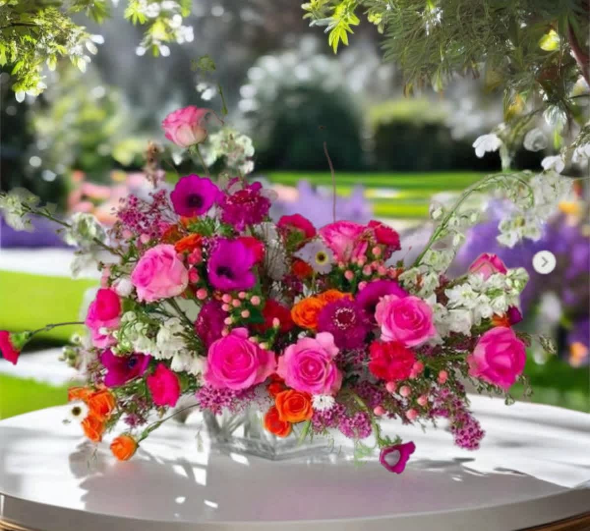 Bright pink and orange floral arrangement in a clear vase