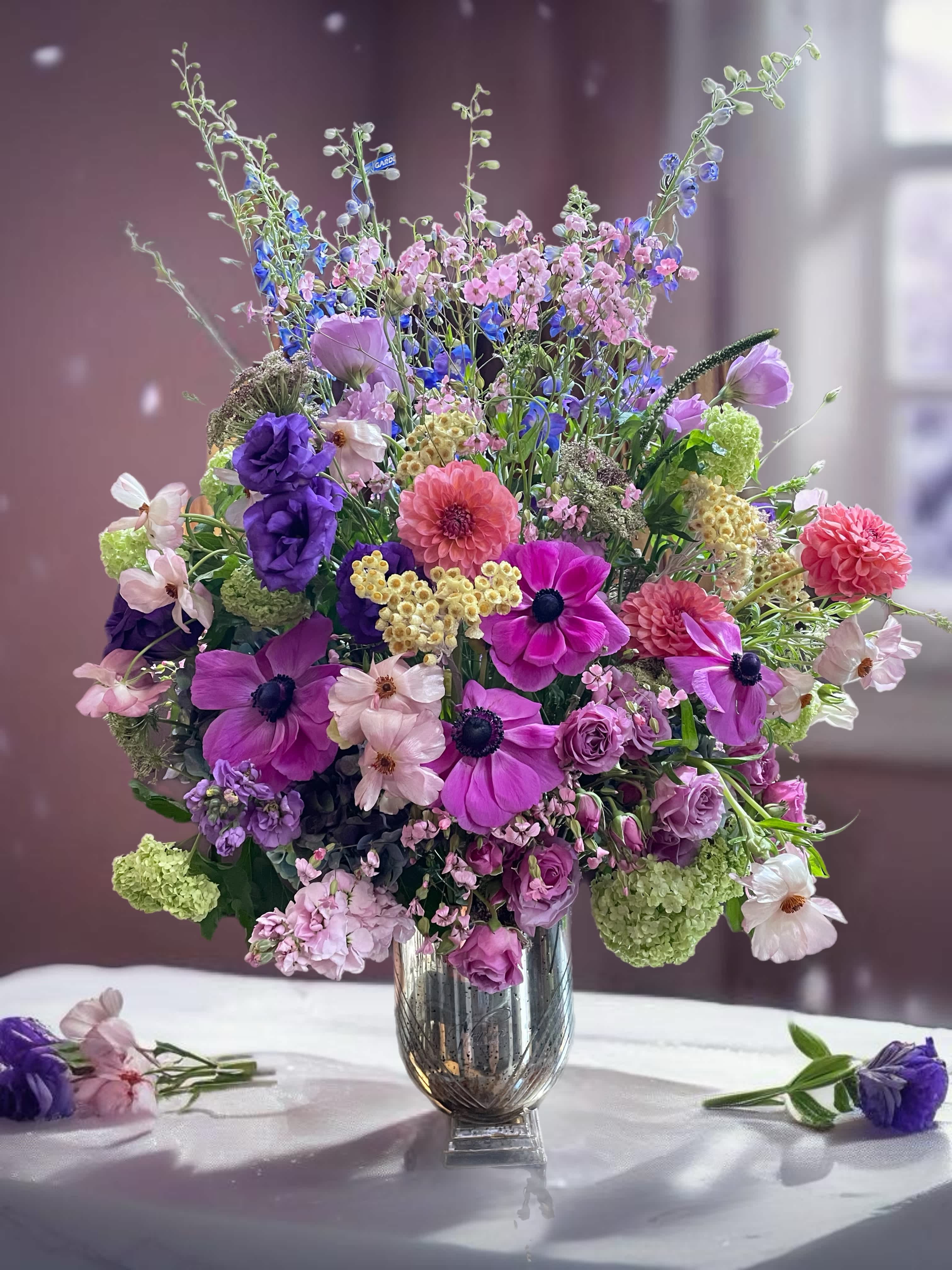 Mixed bouquet of purple, pink, and white flowers in a silver vase