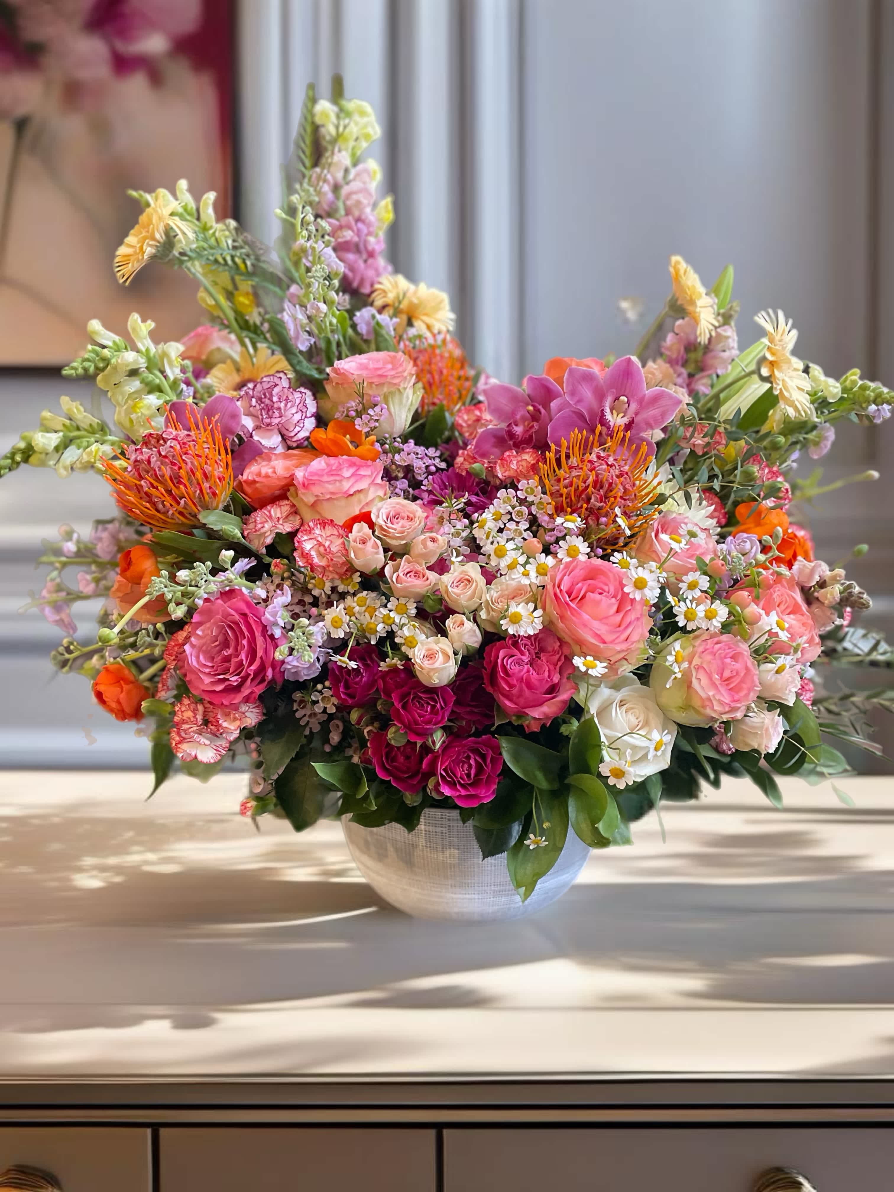 Large mixed flower arrangement in a white bowl vase