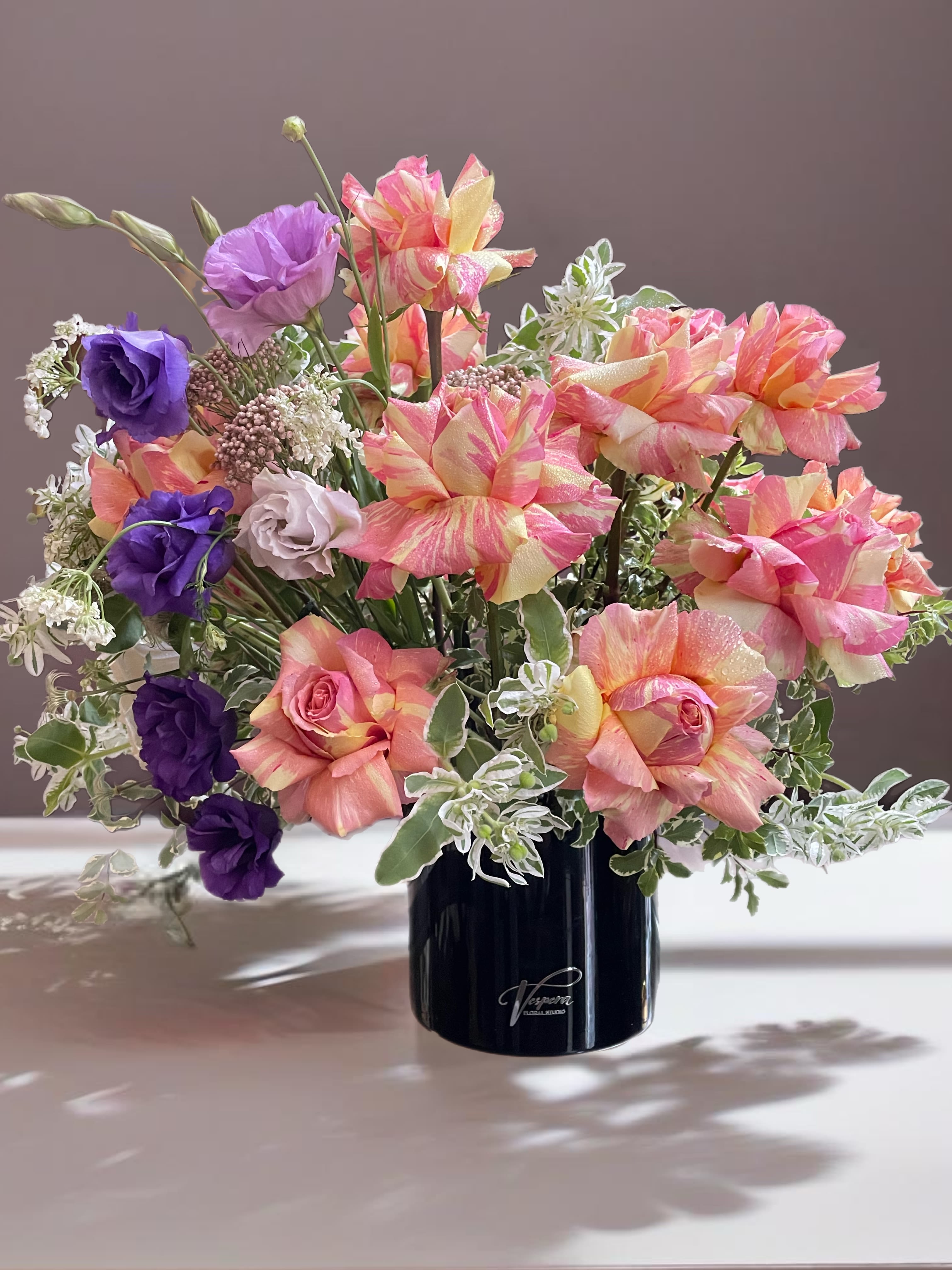 Bouquet of pink, peach, and purple flowers in a black vase