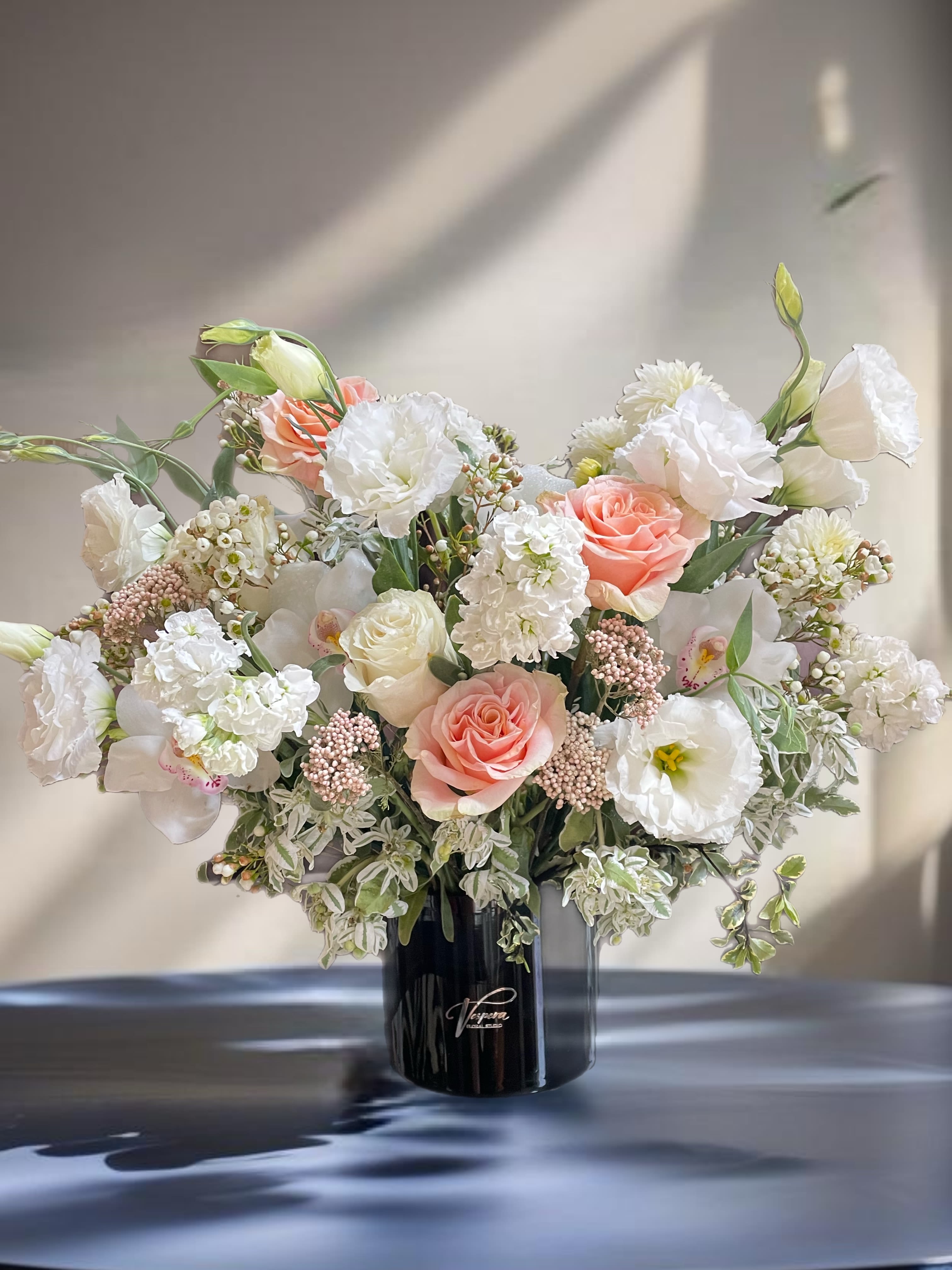 Large bouquet of white and blush flowers in a black vase