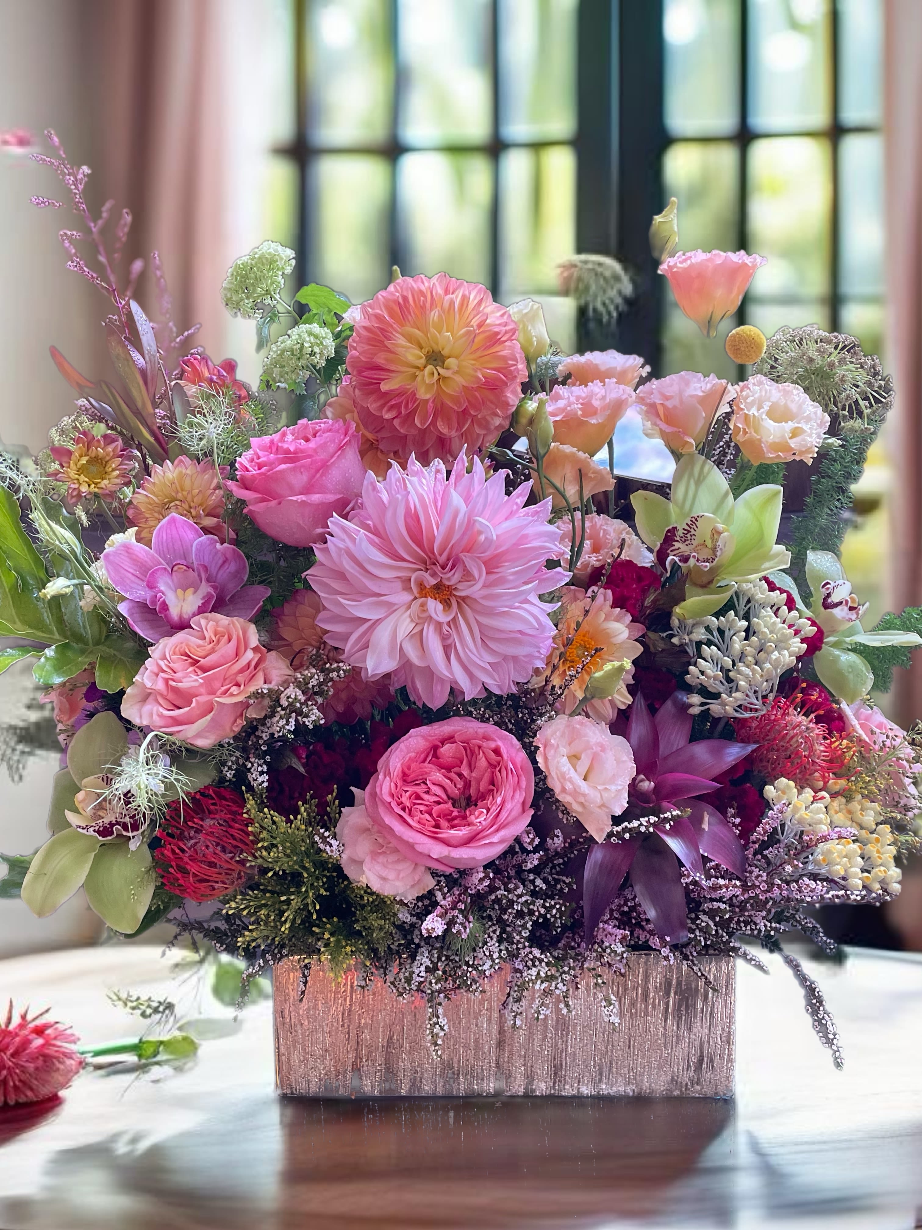 Pink and peach mixed flower arrangement in a square vase