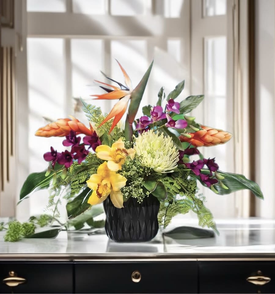 Tropical flower arrangement in a black vase with orange and purple blooms